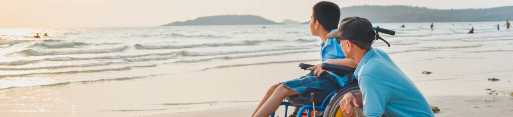 Man and boy in wheelchair on beach
