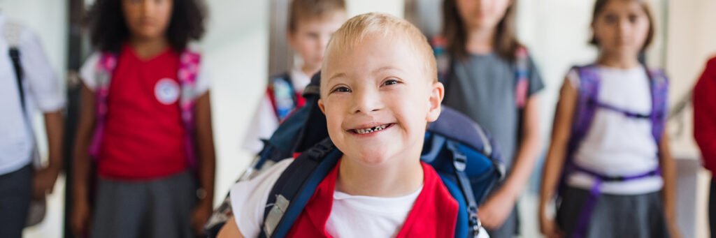 image: school boy with group of children in corridor, walking.